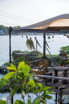 a group of tables and chairs next to a body of water at Baan GoLite Ko Kret - บ้านโกไล้เกาะเกร็ด in Nonthaburi