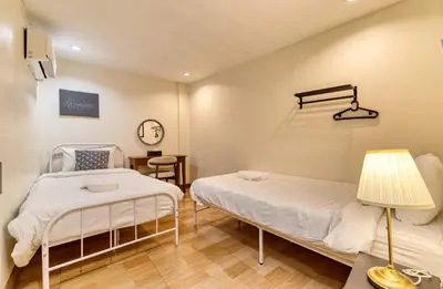 two beds in a room with a lamp and a table at Bangkok Watergate Townhouse \u66fc\u8c37\u4e2d\u5fc3\u6c34\u9580\u5bb6 in Bangkok