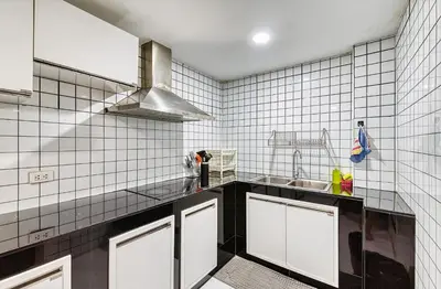 a kitchen with white tiled walls and a sink at Bangkok Watergate Townhouse \u66fc\u8c37\u4e2d\u5fc3\u6c34\u9580\u5bb6 in Bangkok