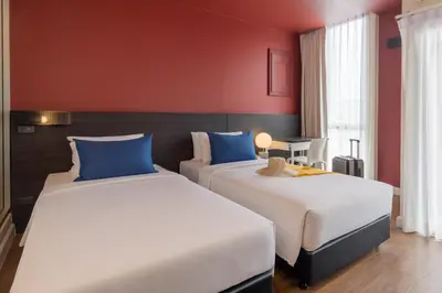 two beds in a hotel room with red walls at Blue Hippo & Red Crocodile Hotel in Bangna