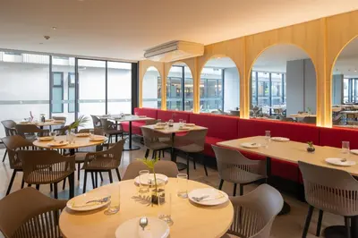 a restaurant with tables and chairs and windows at Blue Hippo & Red Crocodile Hotel in Bangna