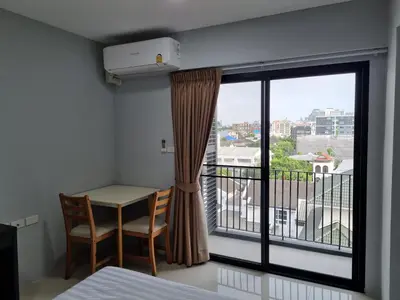 a room with a bed and a table and a window at Tiara Place in Bangkok