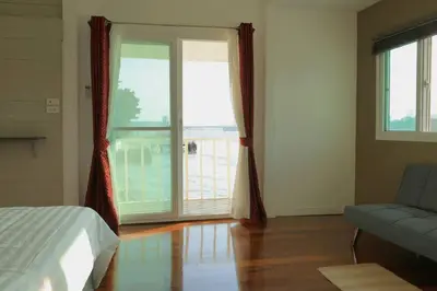 a bedroom with a bed and a couch and a large window at Riverfront house/Chao phraya river/Baan Rimphraya in Bangkok