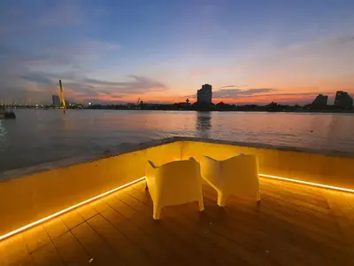 two white chairs sitting on the deck of a boat at sunset at Riverfront house/Chao phraya river/Baan Rimphraya in Bangkok